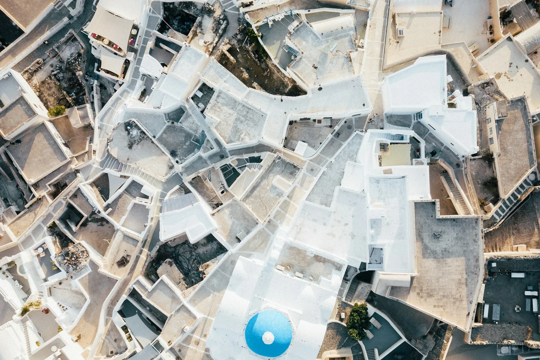 An aerial view of white buildings and a blue dome in Pyrgos, Santorini
